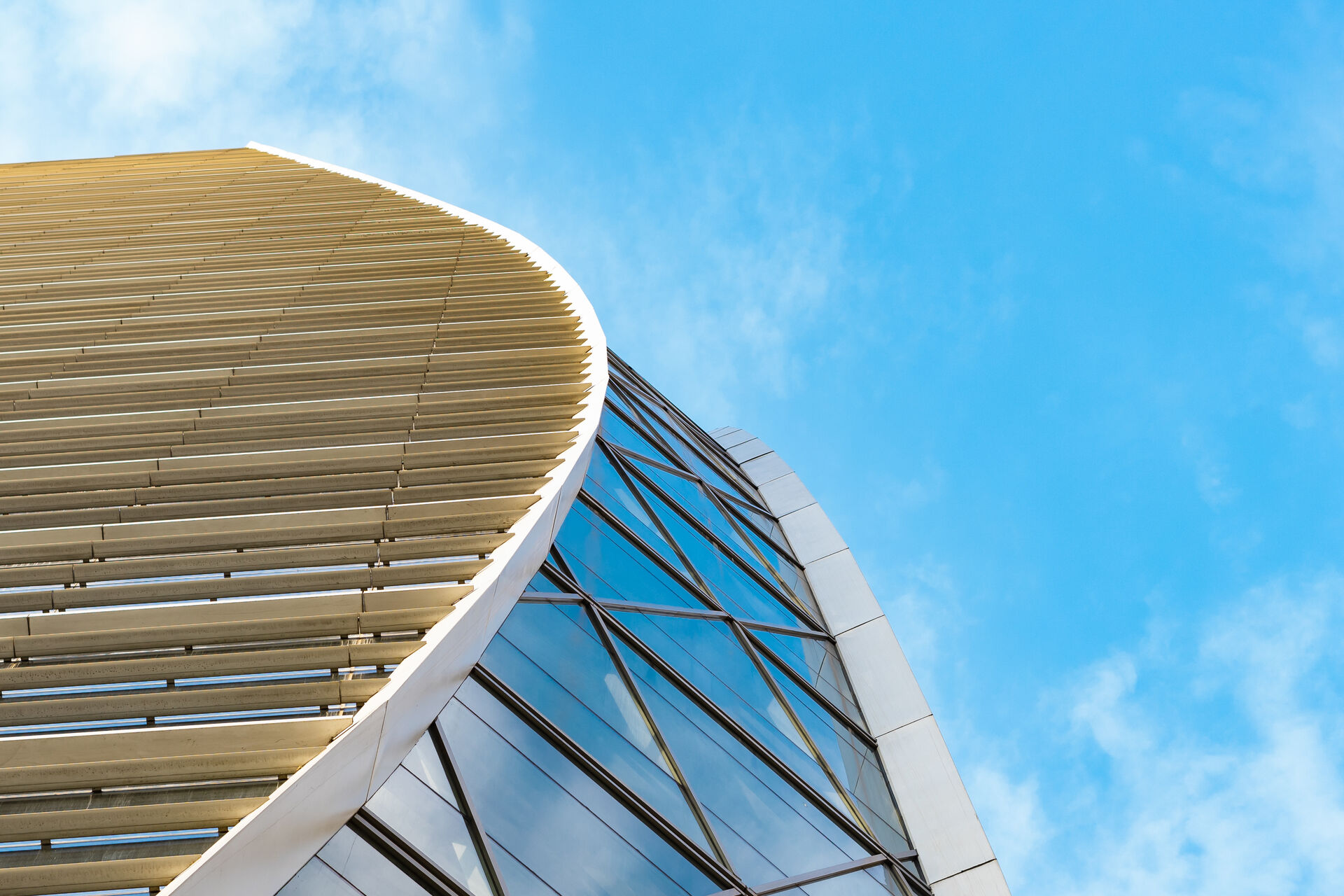 Upward view of a modern high-rise with glass curtain wall against a blue sky